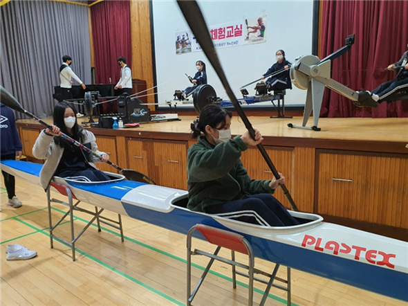 							학생들이 카누에 승선해 패들사용법과 에르고메타에 앉아 카누조법훈련을 하고 있다.